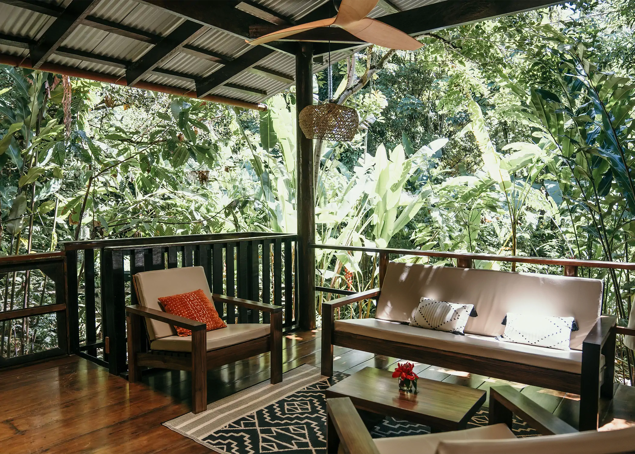 Open-air wooden deck with bench sofa overlooking tropical jungle banana trees