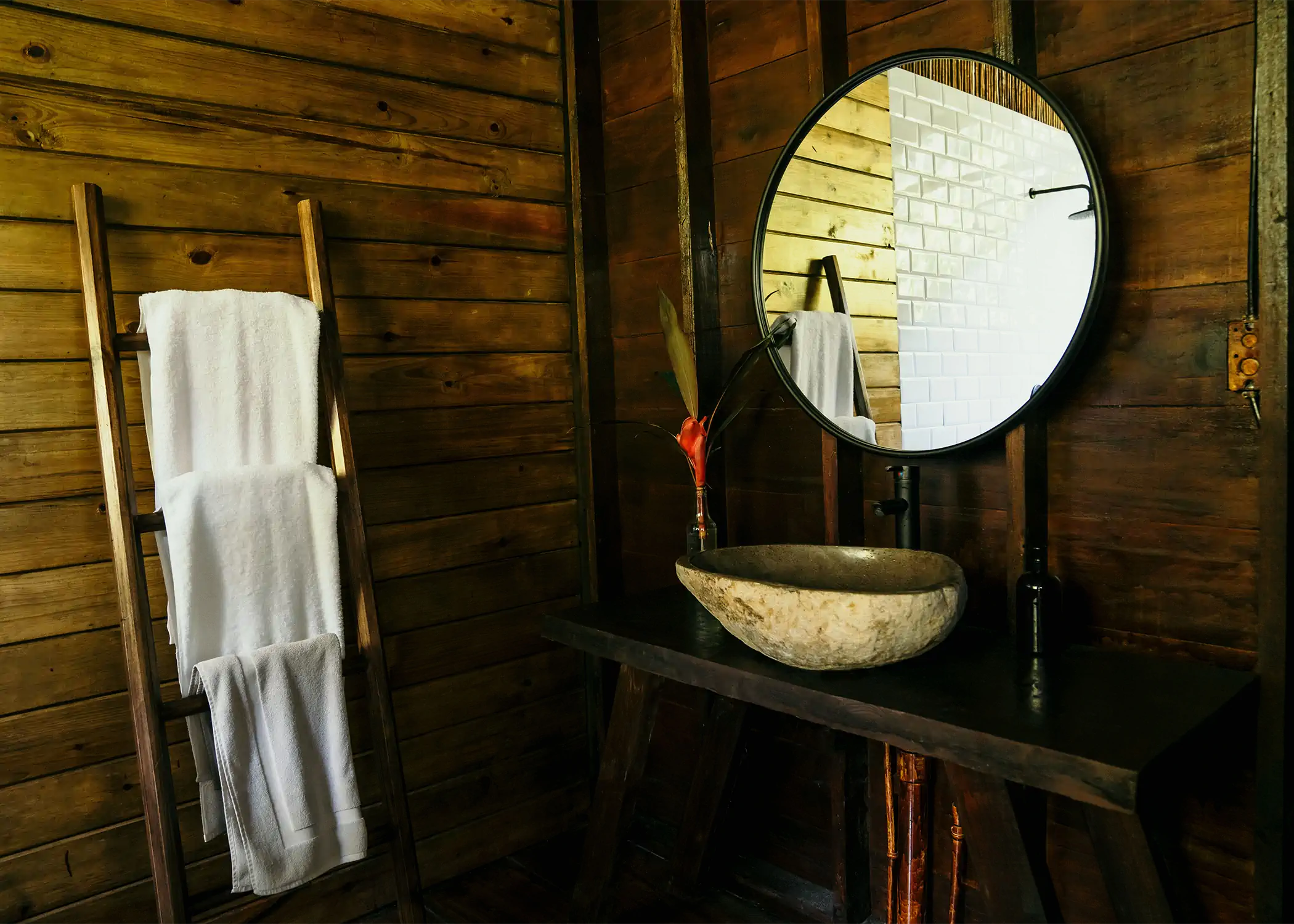 Natural stone vessel sink with round mirror in dark wood bathroom