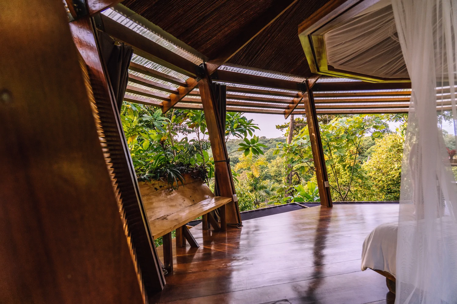 Open-air rainforest bungalow living space with panoramic jungle views
