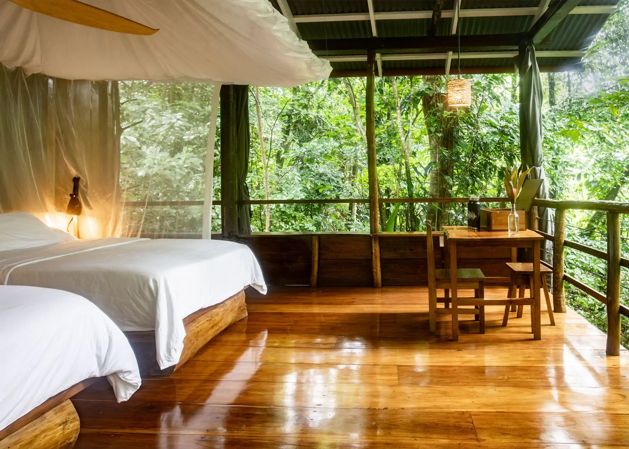 Rainforest bungalow interior with wooden desk overlooking tropical jungle canopy