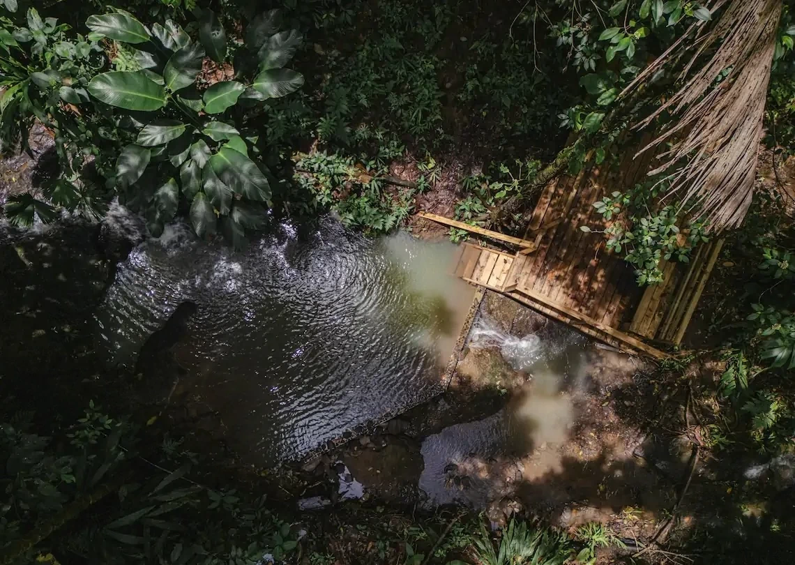 Aerial view of a natural spring-fed rock pool surrounded by rainforest at La Loma, Isla Bastimentos, Panama